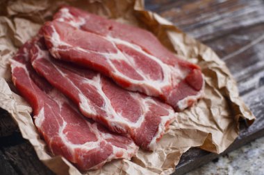 Ahşap masa arka plan üzerinde pişirme kağıdı üzerinde dilimlenmiş taze çiğ et. Domuz boynunu doğrayın. 