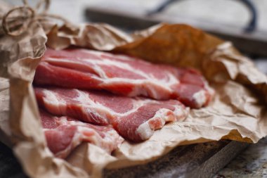 Pişirme kağıdı ve ahşap masa üzerinde taze çiğ dilimlenmiş et.