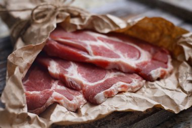 Ahşap masa arka plan üzerinde pişirme kağıdı üzerinde dilimlenmiş taze çiğ et. Domuz boynunu doğrayın. 