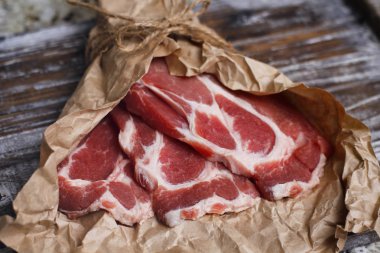 Ahşap masa arka plan üzerinde pişirme kağıdı üzerinde dilimlenmiş taze çiğ et. Domuz boynunu doğrayın. 