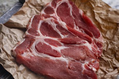 Pişirme kağıdı ve ahşap masa üzerinde taze çiğ dilimlenmiş et.