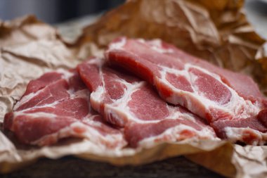 Pişirme kağıdı ve ahşap masa üzerinde taze çiğ dilimlenmiş et.