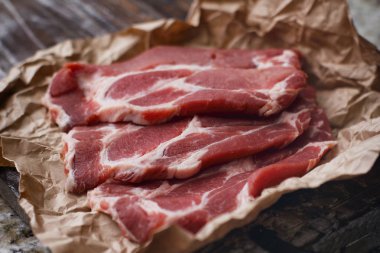 Ahşap masa arka plan üzerinde pişirme kağıdı üzerinde dilimlenmiş taze çiğ et. Domuz boynunu doğrayın. 