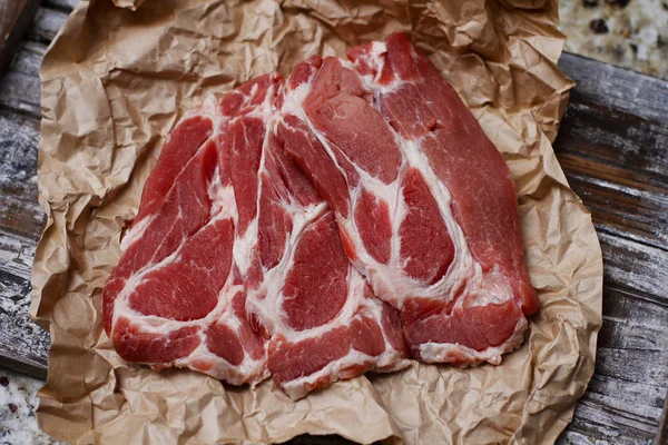 Ahşap masa arka plan üzerinde pişirme kağıdı üzerinde dilimlenmiş taze çiğ et. Domuz boynunu doğrayın. 
