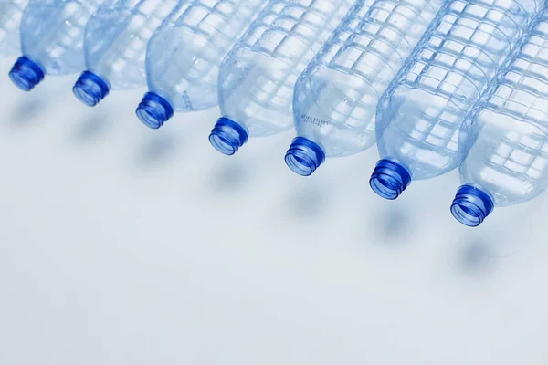 Blue plastic bottles recycle concept background. Empty water bottles on white. Production of pet and packaging.