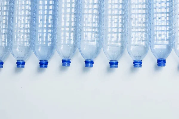 Blue plastic bottles recycle concept background. Empty water bottles on white. Production of pet and packaging.