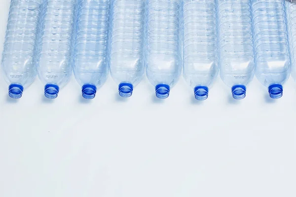 Blue plastic bottles recycle concept background. Empty water bottles on white. Production of pet and packaging.