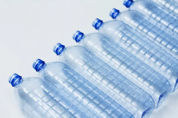 Blue plastic bottles recycle concept background. Empty water bottles on white. Production of pet and packaging.