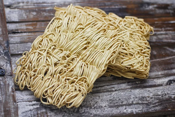 Ahşap masa üzerinde kuru çiğ anlık yumurta erişte seti. Pişirmeye hazır. Sarı geleneksel erişte. Wok. Asya mutfağı.  