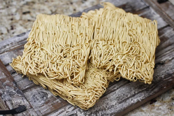 Ahşap masa üzerinde kuru çiğ anlık yumurta erişte seti. Pişirmeye hazır. Sarı geleneksel erişte. Wok. Asya mutfağı.  