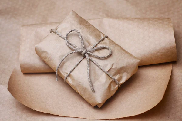 Parcel package wrapped with brown craft paper tied rope. Boxing process.