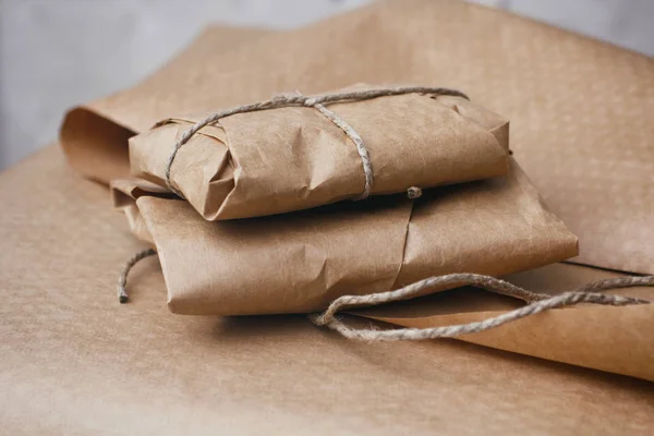 Parcel package wrapped with brown craft paper tied rope. Boxing process.