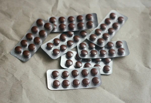 Brown pills plastic clear blisters set on craft paper background. Health care. First aid kit.