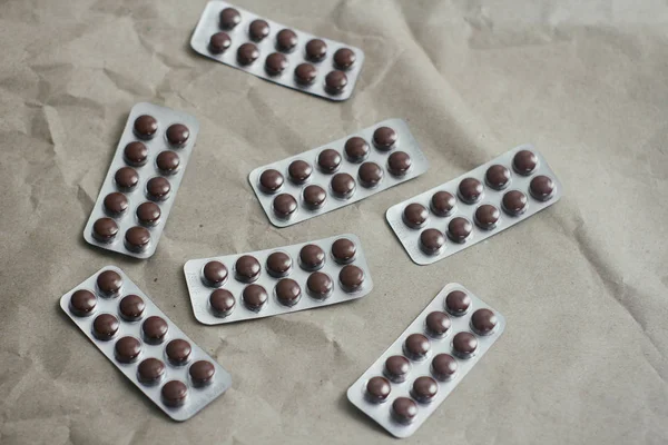 Brown pills plastic clear blisters set on craft paper background. Health care. First aid kit.