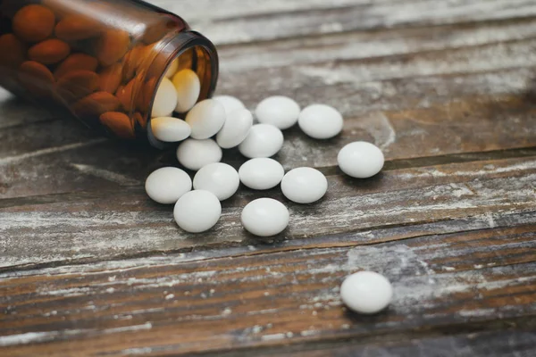 Set of round white pills. Many pills. Yellow glass bottle on wooden table. Aspirin.
