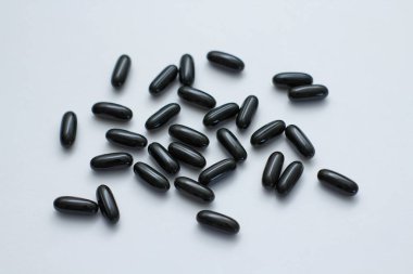 Beyaz arka planda birçok siyah oval hap. Sıvı ile kapsüller. Takviye -leri. 