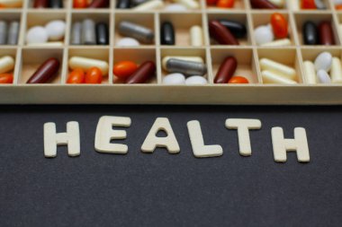 Siyah arka plan üzerinde birçok farklı hap ve kapsül seti ile Pillbox. Metin Sağlığı.