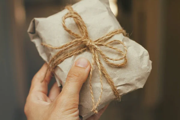 Mão Segurando Pacote Embrulhado Papel Artesanal Com Gravata — Fotografia de Stock