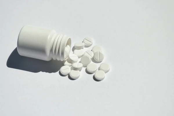 Beyaz arka plan üzerinde yuvarlak düz hapları ile Plastik şişe.