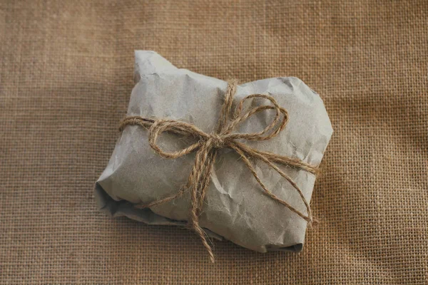 Parcel wrapped into brown craft paper. old cloth background texture. Pouch tie cotton string.