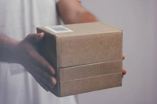 Delivery man with cardboard parcel. Hand holding the delivery box.