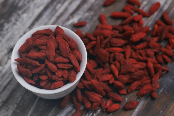 Bayas Goji Secas Una Pequeña Taza Blanca Sobre Fondo Madera —  Fotos de Stock