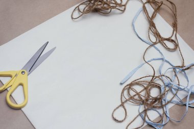Kahverengi el işi kağıt dokusu üzerine yazı yazmak için beyaz sayfa. Makas ve renk iplikleri. Paket dekorasyonu kavramı.