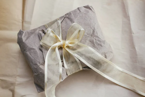 Soft parcel wrapped into old craft paper and tie. Crumpled background texture. Gift shop. Materials for transportation and shipping.