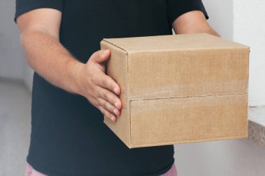 Karton koli ile teslimatçı. Teslimat kutusunu tutan el.