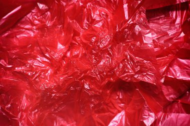 Kırmızı berrak plastik torba doku arka plan. Atık geri dönüşüm konsepti. Buruşturulmuş polietilen ve selofan.