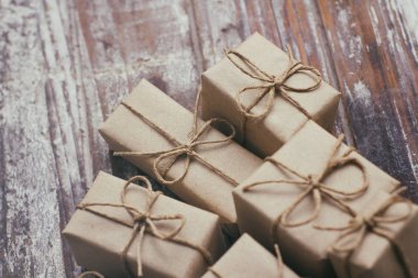 Ahşap arka plan üzerinde kahverengi hediye kutuları seti. Zanaat kağıt sarılmış ve kenevir kablosu ile bağlı. Bir sürü parsel. 