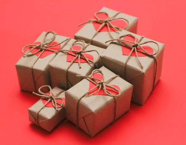 一套棕色的礼品盒 包裹在工艺纸和绑用大麻线 明亮的红色背景和纸箱心装饰卡 — 图库照片