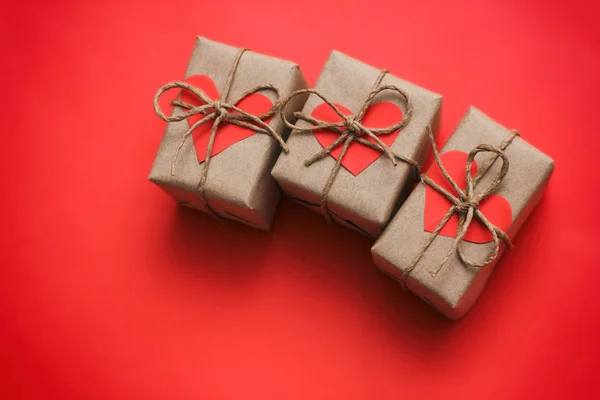 浪漫的礼物集 礼品盒包裹在棕色工艺纸和领带麻绳 纸箱的心 红色实心背景 已交付的包裹 — 图库照片