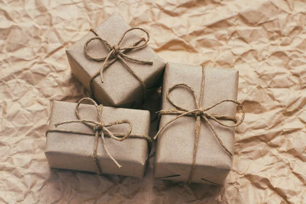 Many parcels wrapped in brown craft paper and tie hemp string. Crumpled background. Presents set. Delivery parcels. Online shopping.