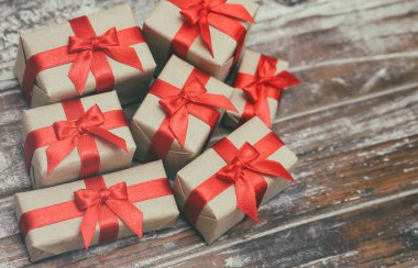 Bazı hediye kutuları kahverengi zanaat kağıt sarılmış ve kravat kırmızı saden kurdele. Dekoratif ahşap arka plan. Metin alanınız. Hediyeler seti.