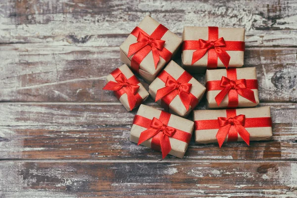 一些礼品盒用棕色工艺纸包裹 系上红色的缎带 装饰木背景 您的文本空间 一套礼物 — 图库照片