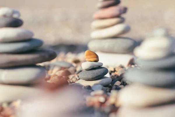 Zen pyramid of spa stones on the blurred sea background. Sand on a beach. Sea shores. Place for text.