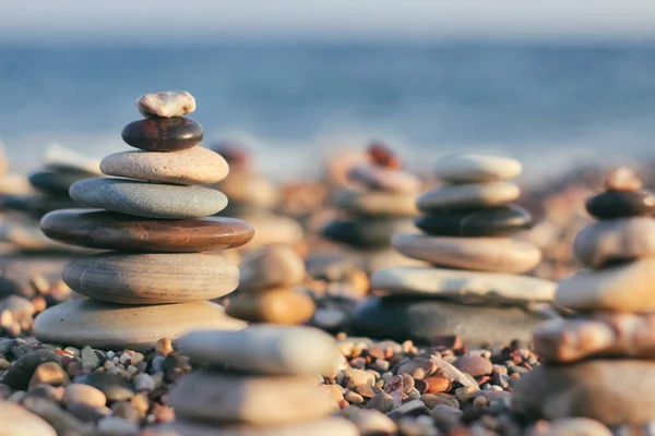 Zen pyramid of spa stones on the blurred sea background. Sand on a beach. Sea shores. Place for text.