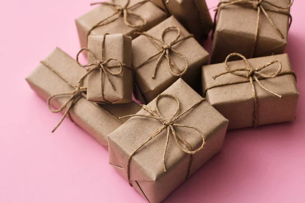 一套许多目前包装在棕色工艺纸和领带绳的箱子 粉红色背景纹理 递送包裹 礼品店概念 — 图库照片