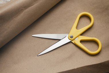 Zanaat kahverengi kağıt doku arka plan üzerinde sarı makas. Paketleme işlemi. Hediye ve çiçek dükkanı. Nakliye hizmeti. Ambalaj aksesuarları.