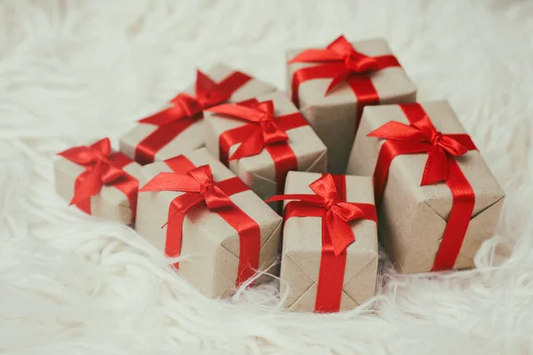 一些礼品盒用棕色工艺纸包裹 系上红色的缎带 白色毛皮背景 您的文本空间 一套礼物 — 图库照片