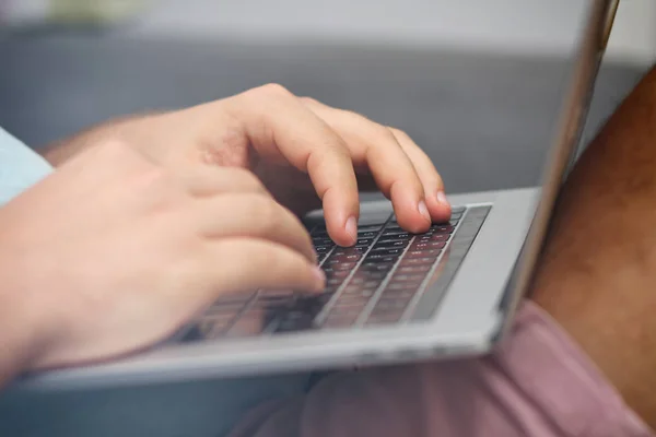 Young man typing on a laptop keyboard. Close-up details. Man\'s hands.  Working online. Freelance concept. Shop on the couch. Online shopping.