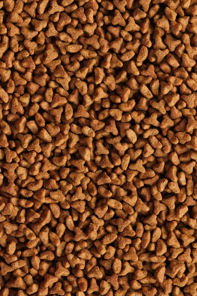 Dry cat food texture background. Medium size triangular pieces. Food pattern. Chewing treats for pets.