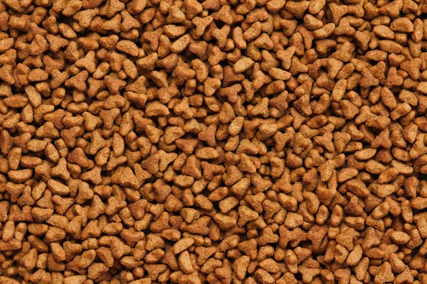 Dry cat food texture background. Medium size triangular pieces. Food pattern. Chewing treats for pets.