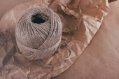 A csomagolási parcellák folyamata. Zacskó csomagolva barna kézműves papírt és nyakkendő kender vezetéket. Gyűrött papír textúra háttérben. Kézbesítési szolgáltatás. A megrendelés. Online vásárlás.