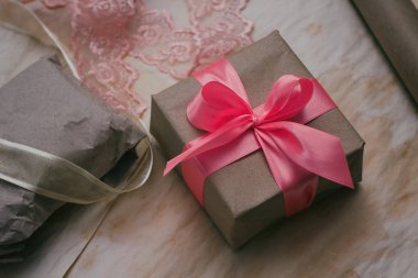 Hediye kutusu kahverengi zanaat kağıt sarılmış ve pembe saden kurdele ile bağlı. Paketleme işlemi. Hediyelik eşya dükkanı. Düğün dekoru.