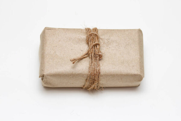 Упаковка в коричневой ручной бумаге и нитка для галстука конопли. Посылка. Служба доставки. Интернет-магазины. Ваша покупка. Подарочная коробка на столе. Изоляция на белом
. 