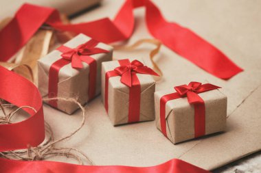 Zanaat kağıt sarılmış hediye kutuları seti ve kravat kırmızı saden kurdele. Noel hediyeleri. Tatil havası. Yeni yıl dekoru.