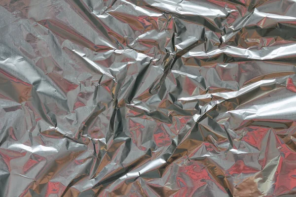 Crumpled foil texture background. Metal  paper shit. Silver aluminum surface.  Gift wrapping shiny paper. Glitter effect.