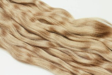 Beyaz arka planda açık kahverengi dalgalı insan saçı. Güzellik salonu. Saç Uzantıları. 